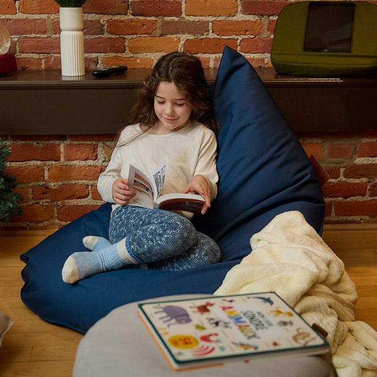 Enfant en bas âge relaxant en lisant un livre dans un bean bag Junior ARICO.
