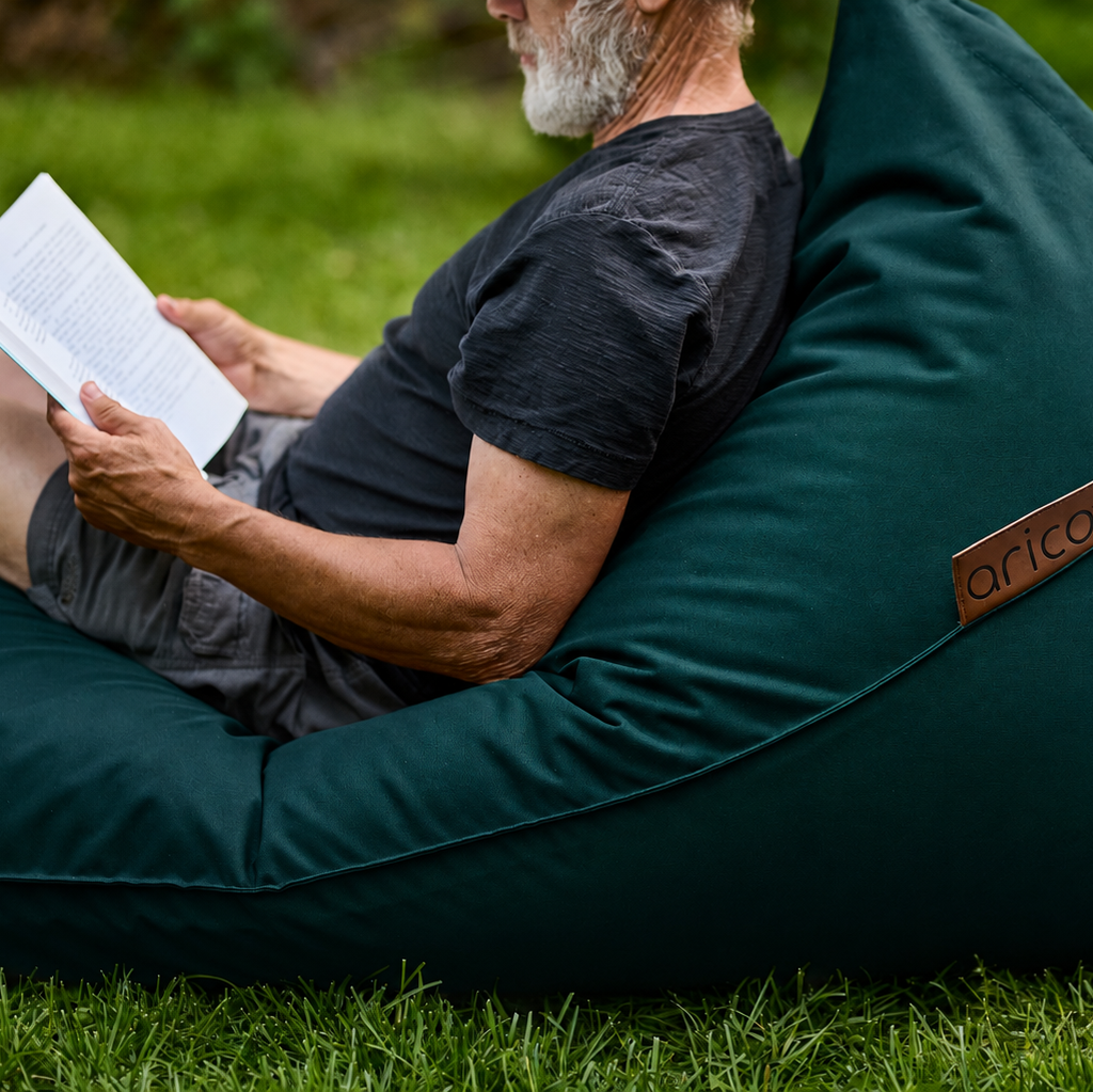 Homme lit dans un bean bag Lounge Adulte, assis confortablement à l'extérieur, ambiance paisible, soleil apaisant et le confort ultime!