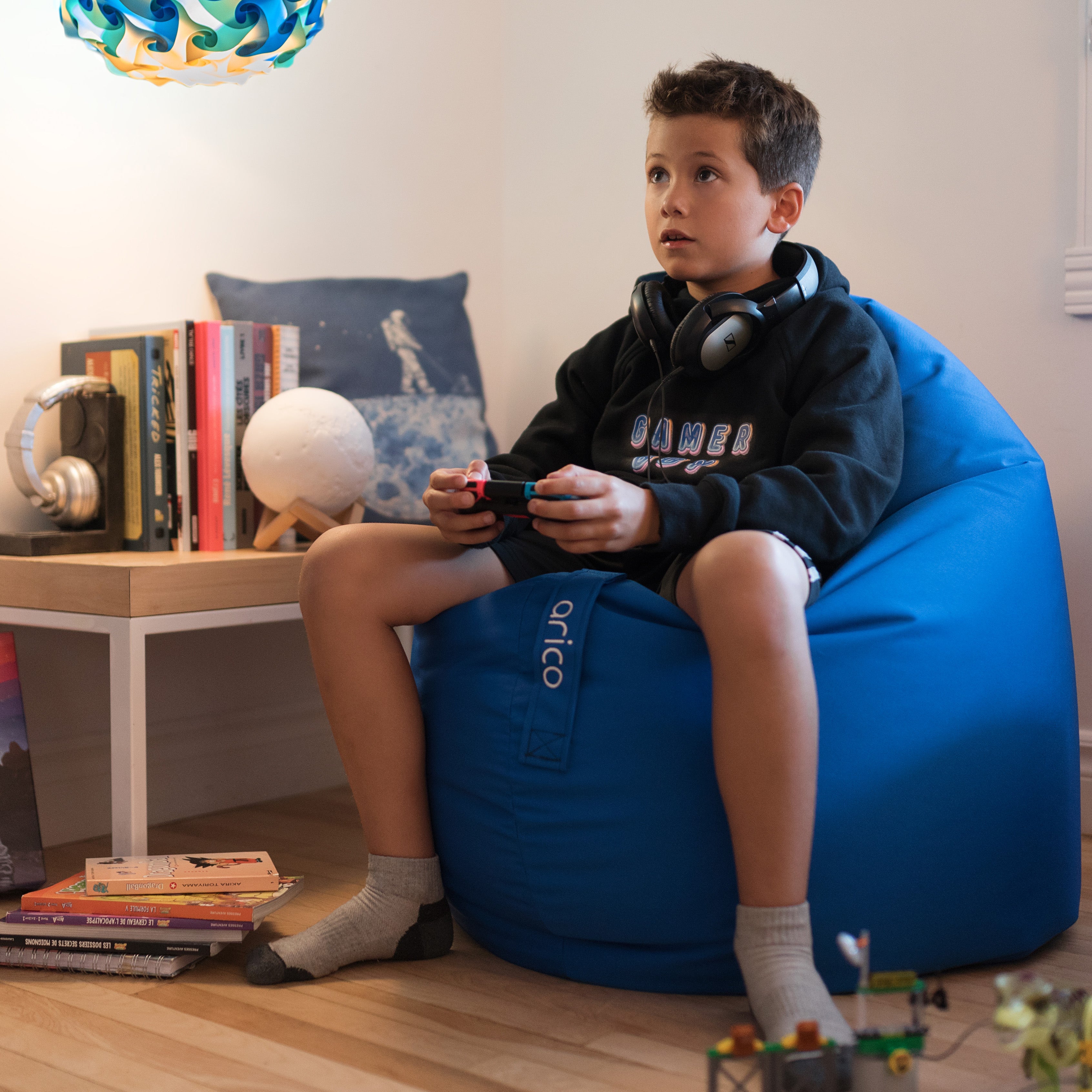 Coussin de sol de couleur indigo dans une salle de jeux avec enfant jouant à la console.