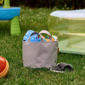 Panier de rangement Arico de couleur Boréal avec jouets à l'extérieur dans une cour. 