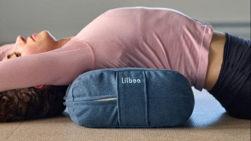 A woman using a Lilbee bolster, during Yoga practice, calm and quiet atmosphere. 