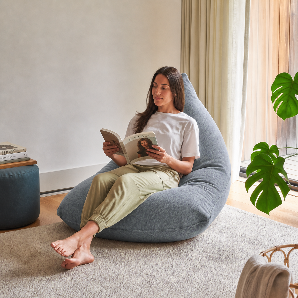 Femme lisant dans un bean bag Lounge Adulte ARICO de la collection Sereny, couleur Gris ciel. Fauteuil lounge confortable en tissu texturé, idéal pour un coin lecture, la détente et les moments de relaxation à la maison. Fabriqué au Canada.