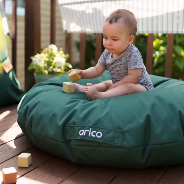 Enfant dans un coussin de sol ARICO de couleur Boréal vert. 