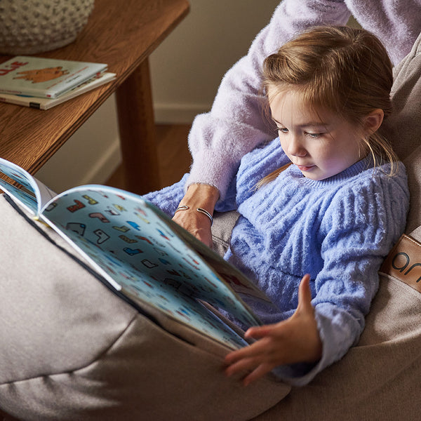 Petit fille lisant son livre avec un RICO dans un bean bag ARICO. 