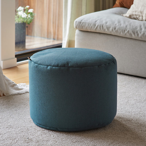 Pouf repose-pieds Arico de couleur récif dans un décor maison. 